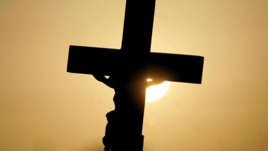 FILE -- A cross is silhouetted against the sun outside the Woodside Hospice in Pinellas Park, Fla.